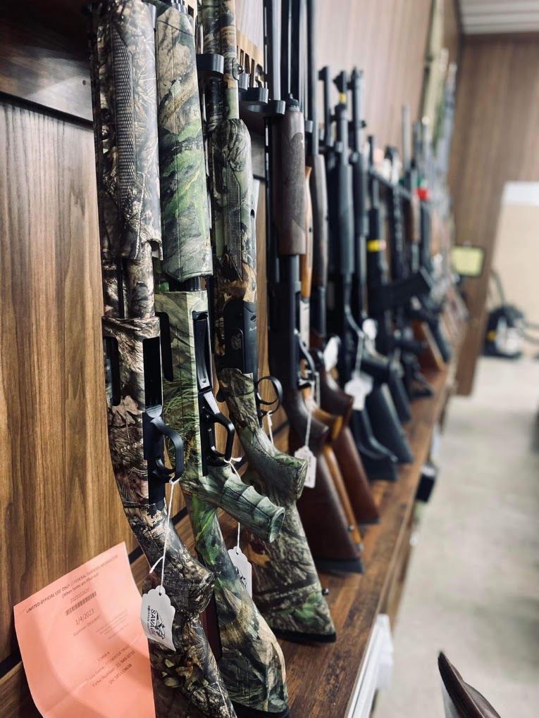 A row of shotguns and rifles racked along the shop wall