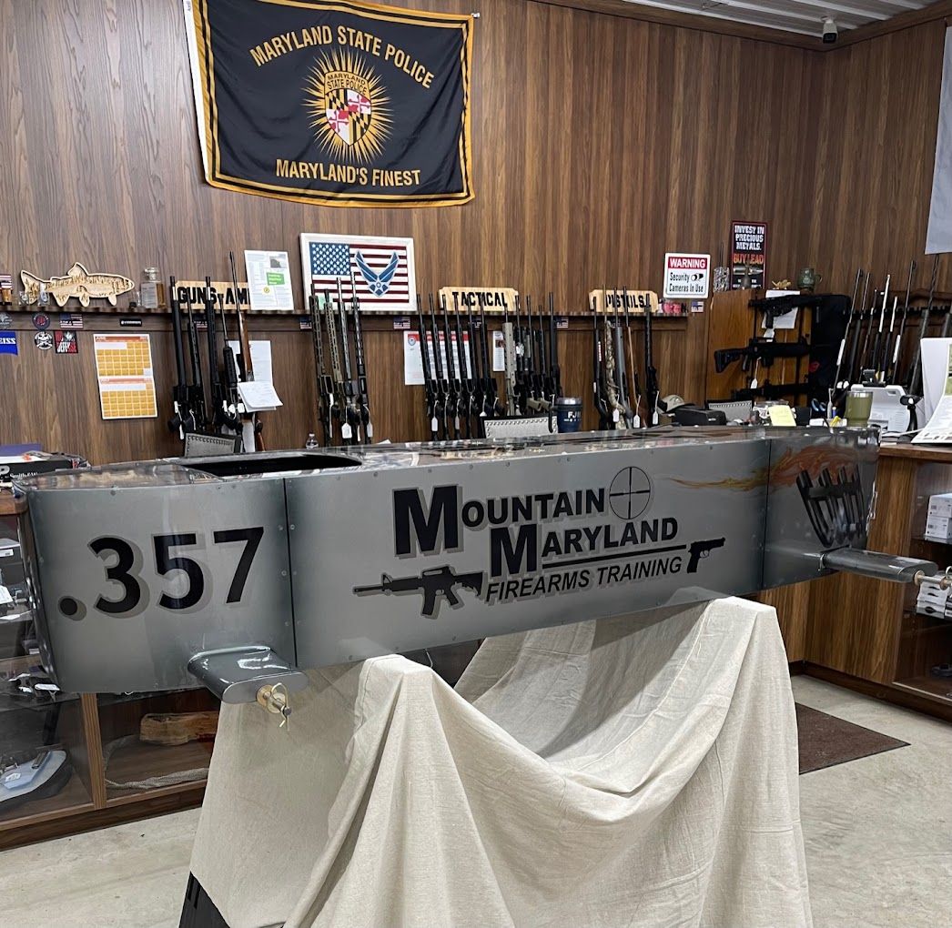 Inside the shop: rifle racks, the Maryland State Police flag, and the Mountain Maryland Firearms Training sign